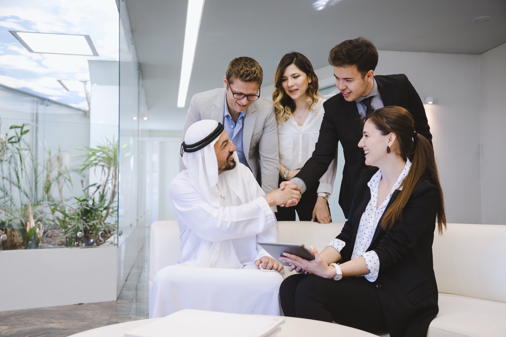 Acmatic partners shaking hands with clients during a meeting